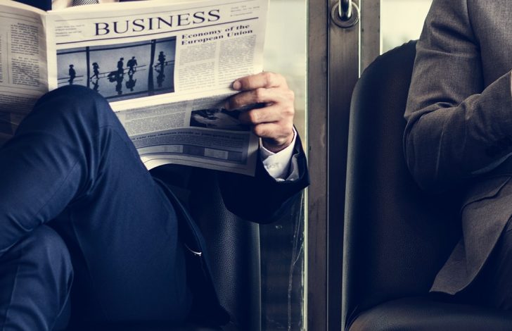 two business brokers sitting reading a business newspaper