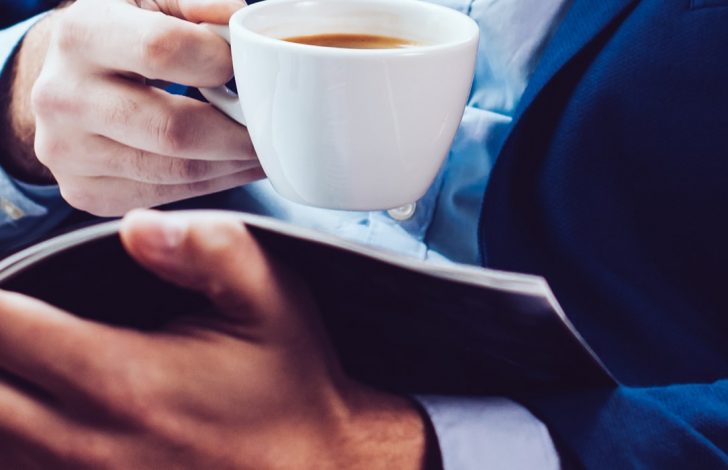 close up of business man drinking coffee and reading information