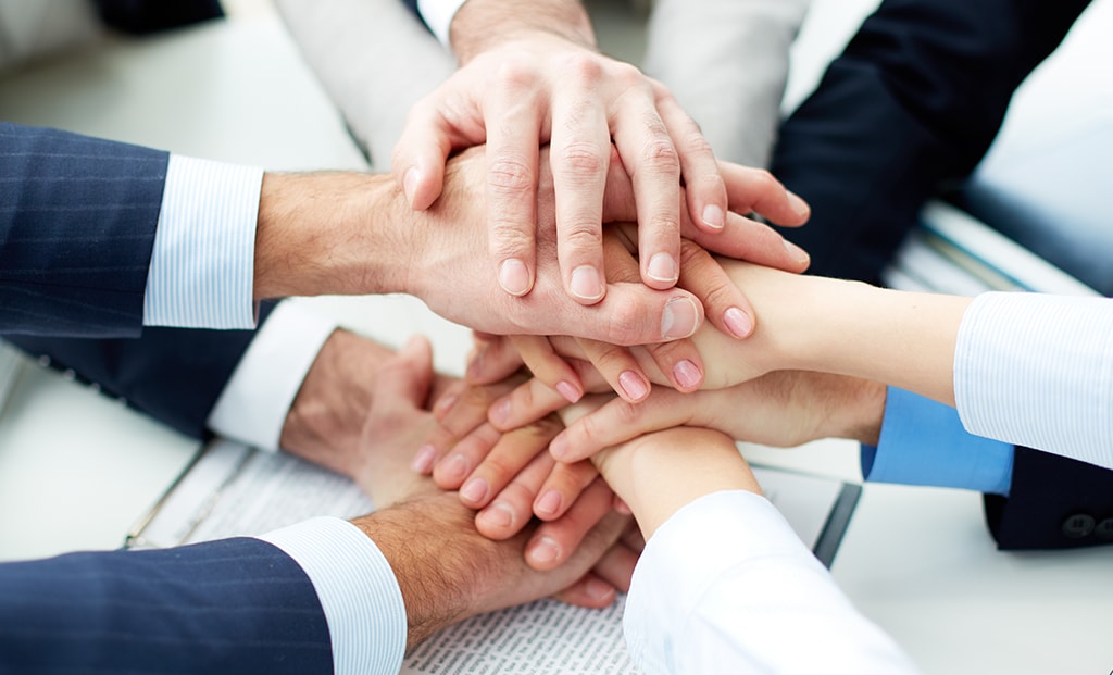 group of business brokers putting their hands in the middle