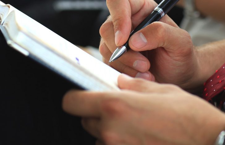 close-up of gentleman writing in his notebook.