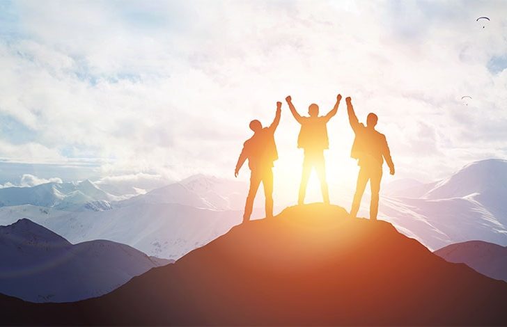 business brokers successfully reaching top of mountain at sunrise