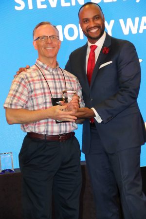 presentor smiling with award winner with his award