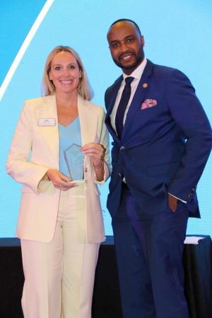 woman business broker smiling with award on stage with gentleman
