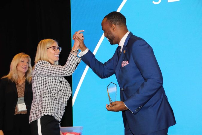 two business brokers high fiving on stage while receiving award