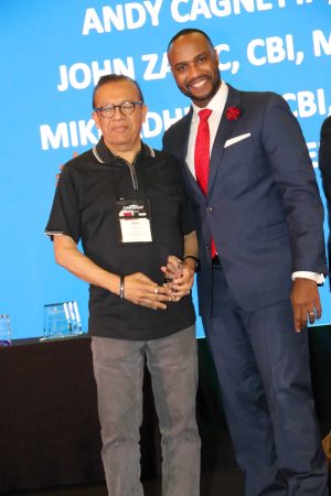 Mike smiling with his award on stage with presenter