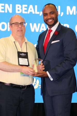 two gentleman smiling on stage with award