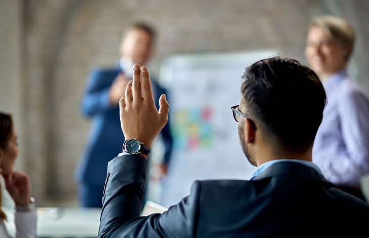 back of man raising hand to ask question about business brokerage