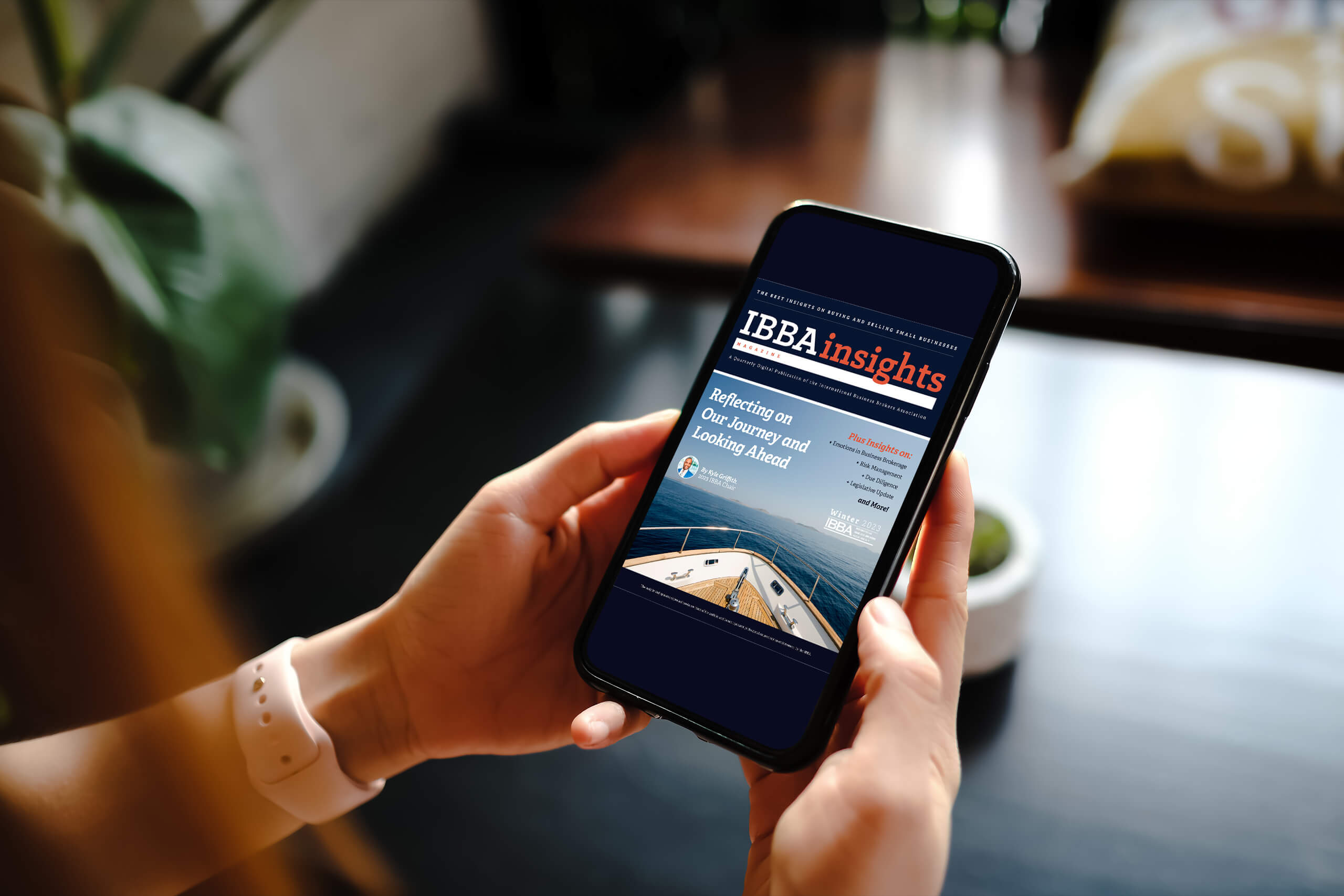 woman holding phone with ibbainsights winter 2023 displayed