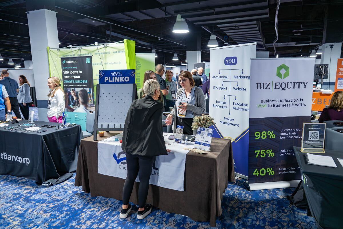 A presenter speaking to an attendee at their booth at the 2026 IBBA Conference